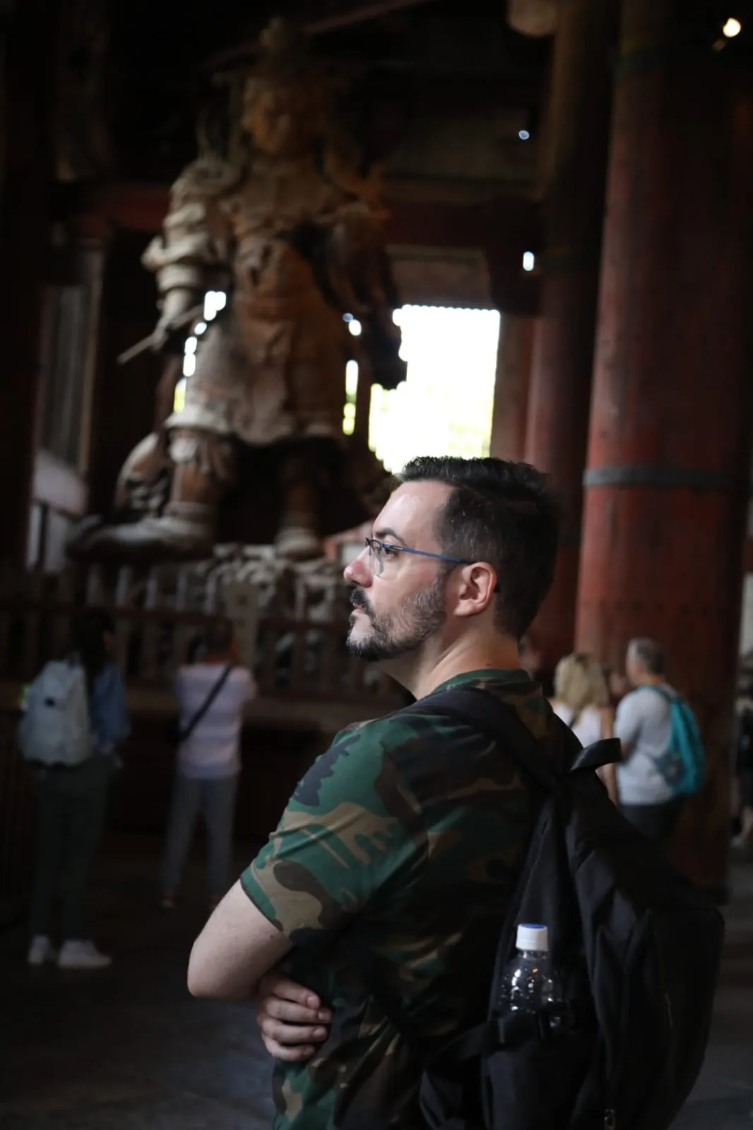 Robugin di profilo davanti a una grande statua guardiana di legno nel Todai-ji