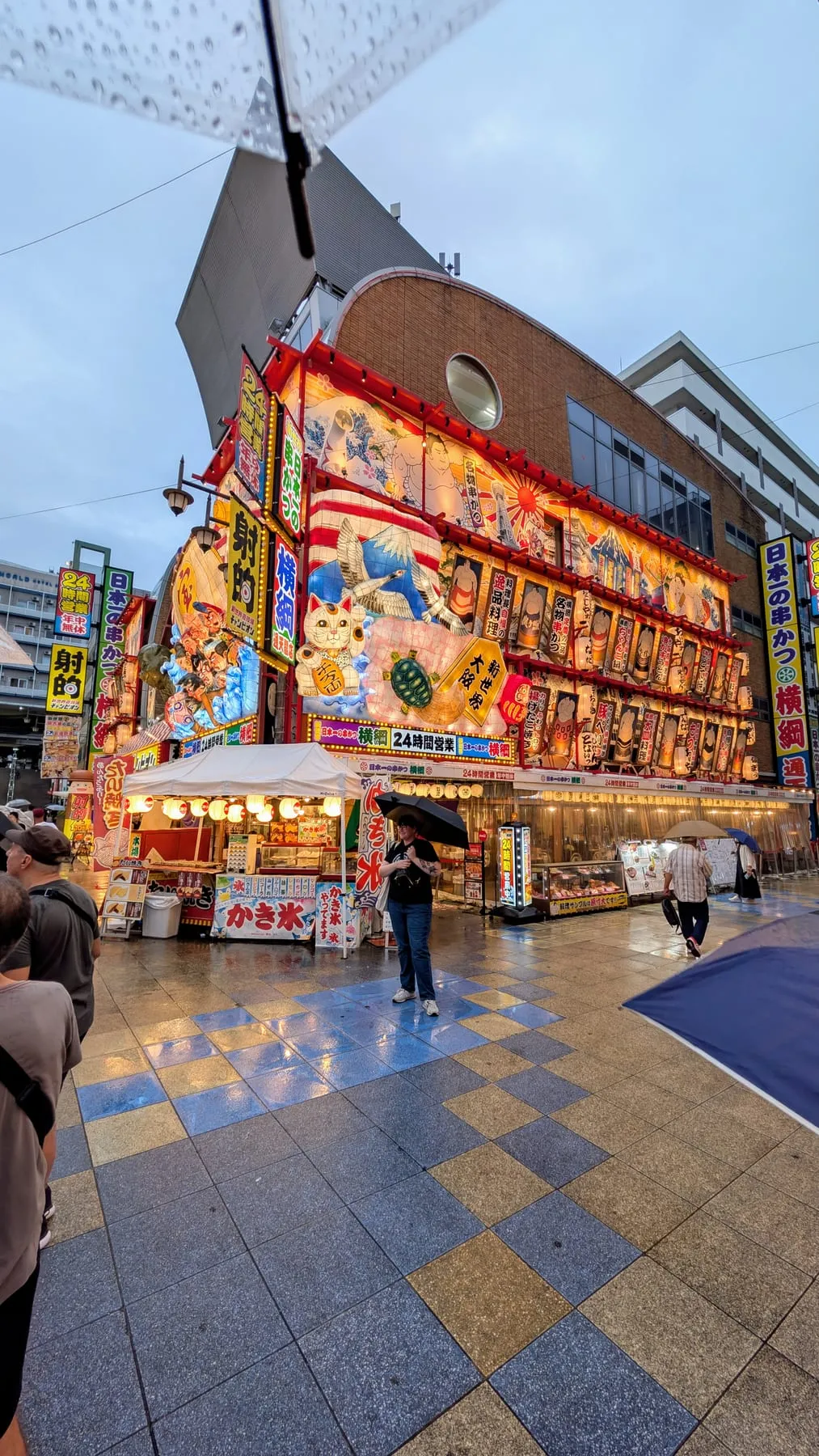 Edificio coloratissimo pieno di insegne nel quartiere Shinsekai di Osaka sotto la pioggia