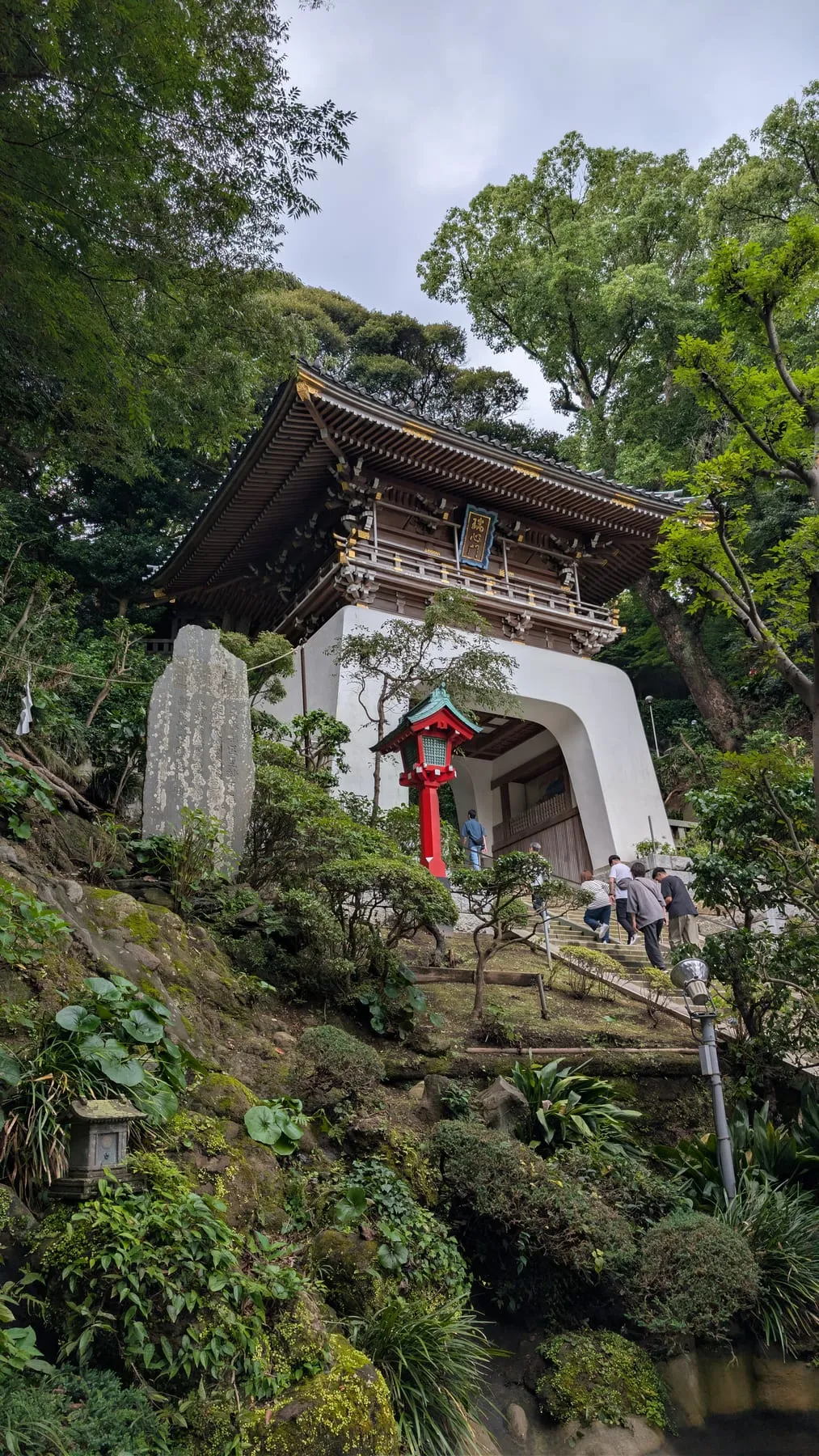 Il portale del santuario di Enoshima tra la vegetazione, con scalinata in pietra