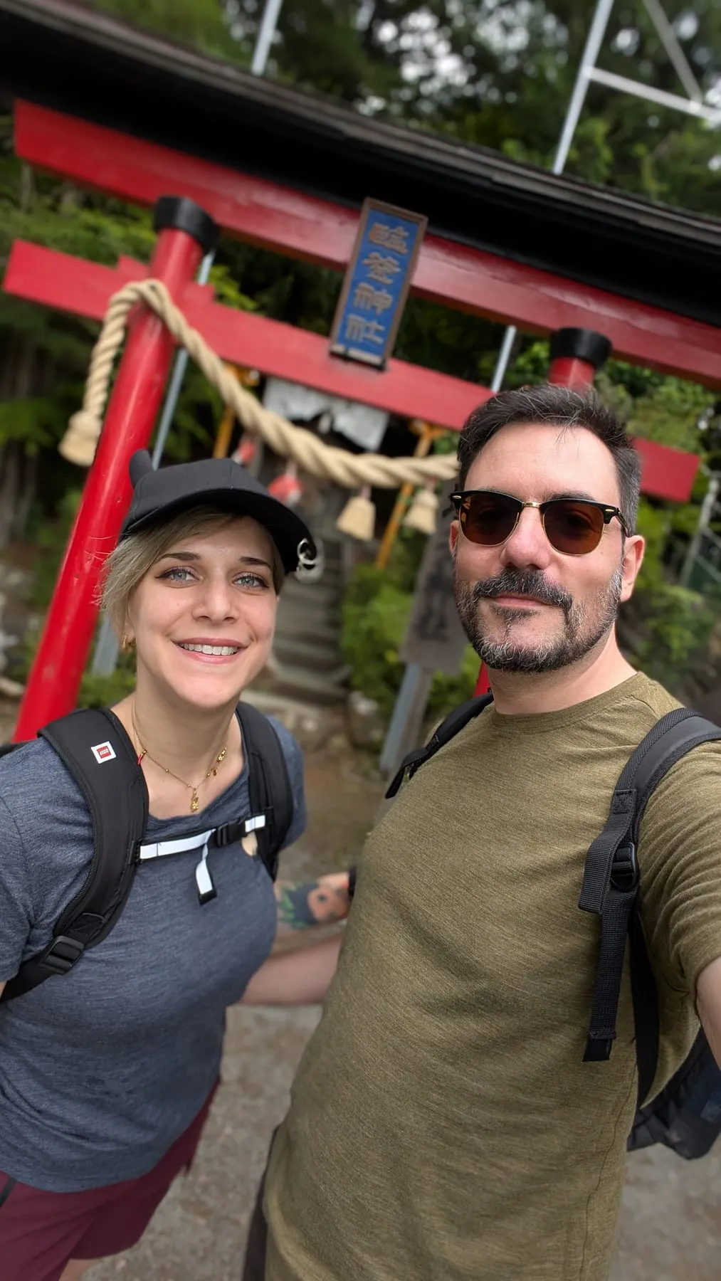 Robugin e Corviskiddo in un selfie davanti a un torii rosso con la corda sacra, zona del Monte Fuji