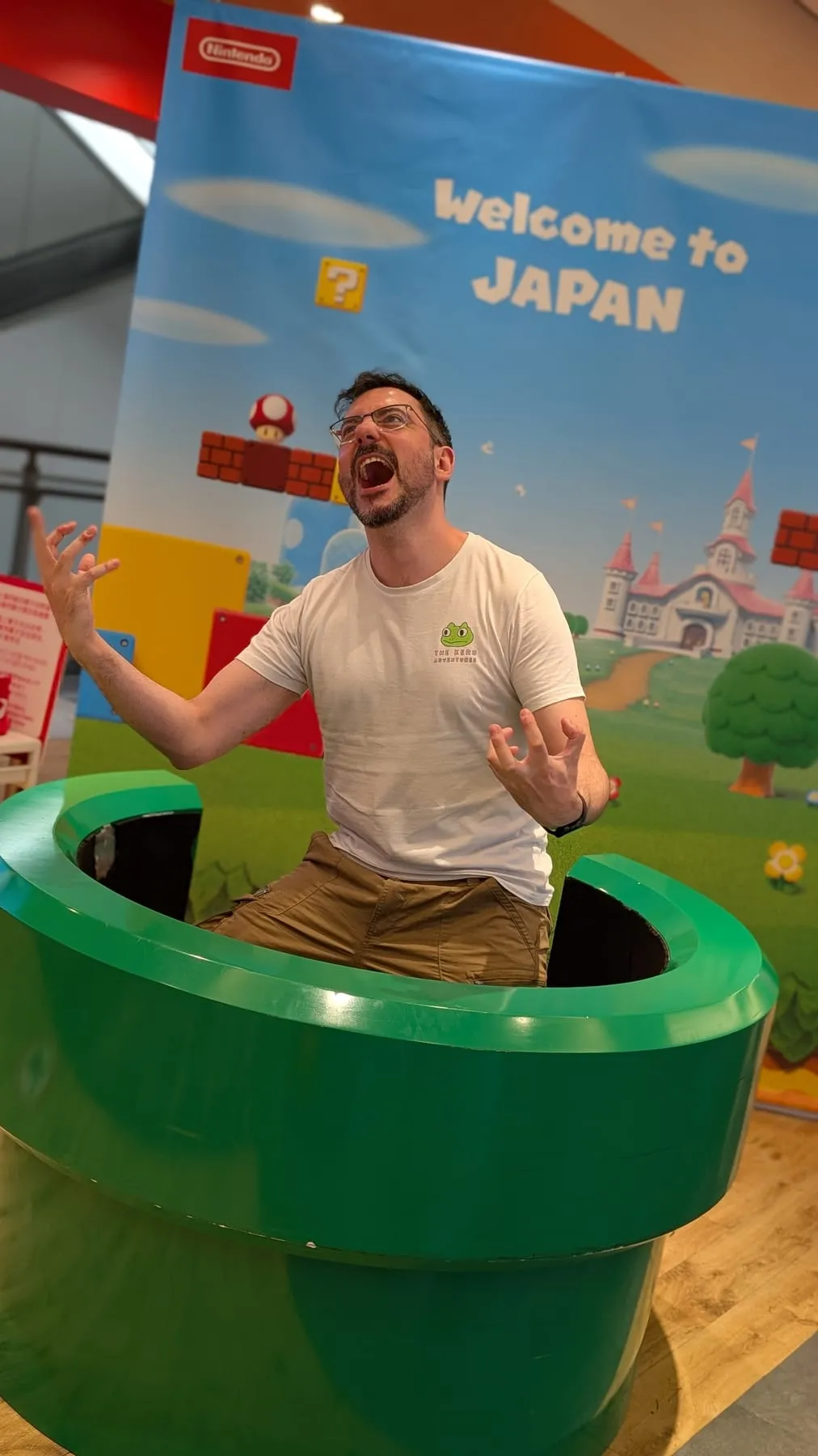 Robugin dentro un tubo verde di Super Mario davanti alla scritta Welcome to Japan